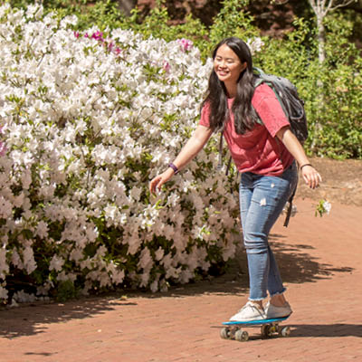 Student skateboarding down a brick walkway.