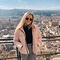 female student sitting in front of a city in Italy