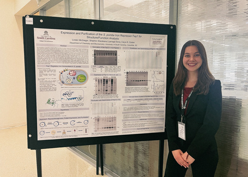 McGregor standing next to her research presentation board.