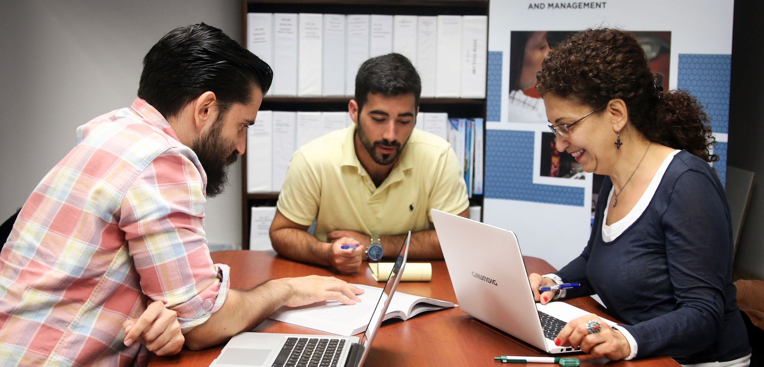Group of people sitting around a table using laptop computers.