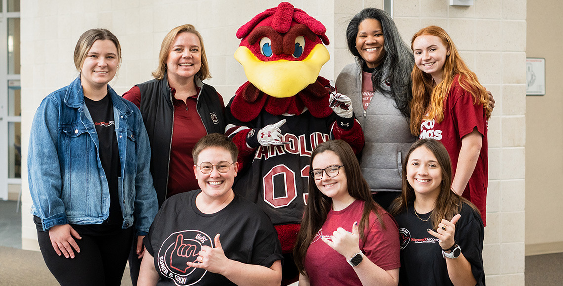 SAPE peer educators and staff stand with Cocky, smiling