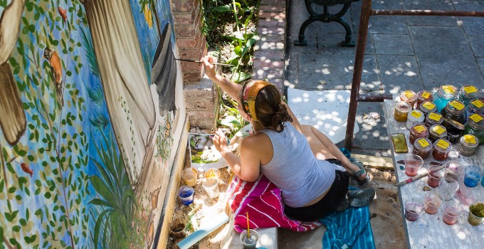 a student paints a mural as part of a creatie endeavor