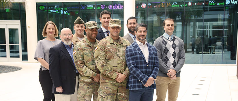 students in plain clothes and uniforms standing in front of the Darla Moore School of Business