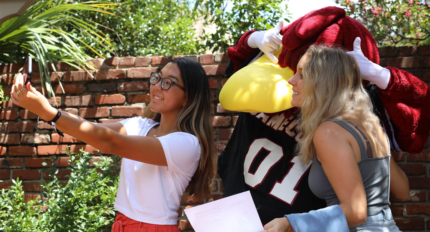 Cocky taking a selfie with a couple of students.