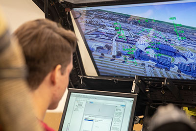 Over the shoulder of a person in a helicopter flight simulator.