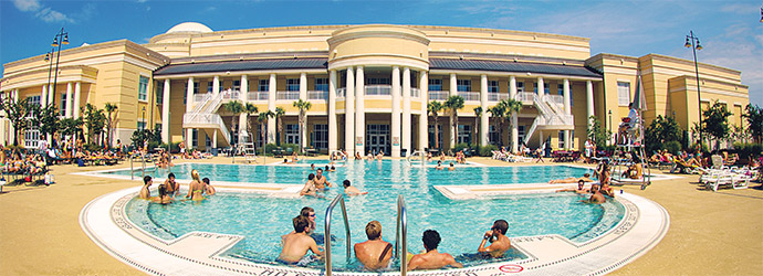 Students sitting around the outdoor pool at the fitness center on a beautiful sunny day.