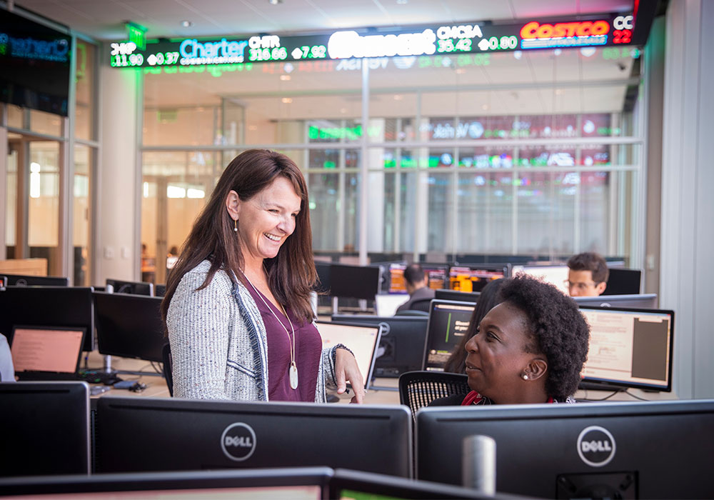 Professor talking with a student in a computer lab.