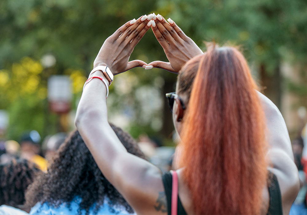 Student holding up an A sign in front of a group of people.