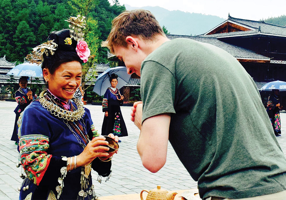 Joe Toomb bowing at a woman in full asian culture dress while studying abroad in China.