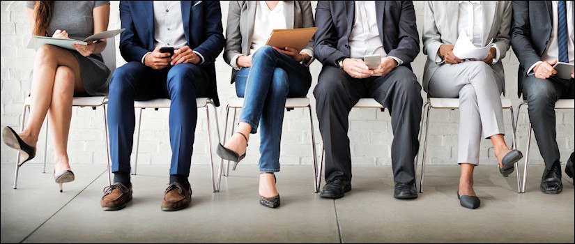 Waist-down view of sitting job applicants in waiting room