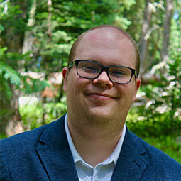 man with dark glasses on smiling outside