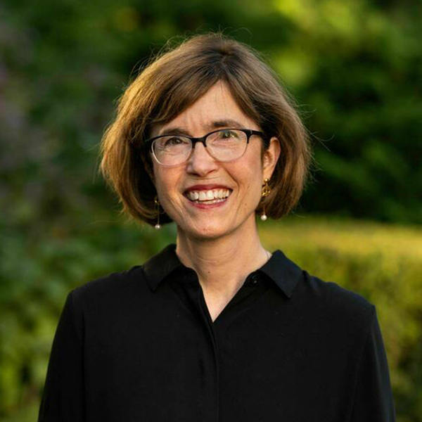 Headshot of a woman with short brown hair wearing a black button up shirt standing outside