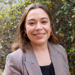 woman smiling with brown hair and a houndstooth jacket on