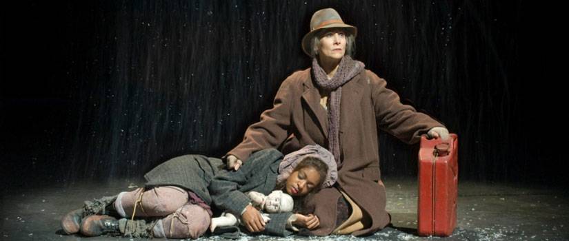 Two people on stage with snow in "Mother Courage"