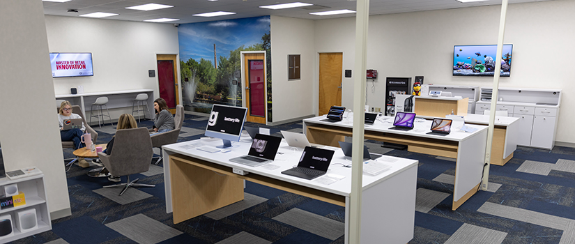 The Gamecock iHub space on the seventh floor of Close-Hipp. Laptops sit on tabletops. Three students sit around a table.