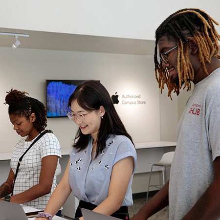 Three customers look at Apple products while visiting the Gamecock iHub.