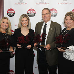 2018 Alumni Award winners Alumni Award winners stand holding their awards in front of the HRSM Alumni Society step and repeat banner