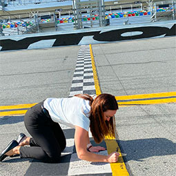 Julia McAleer Julia McAleer kneels on the Daytona Raceway and signs her name on the pavement of that legendary racetrack