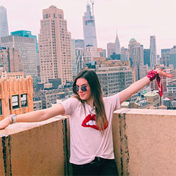 Sara Pollin Sara Polllin, with arms spread wide, stands on a patio overlooking New York City buildings