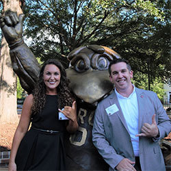 Tara Parker and Blake Edmunds Tara Parker and Blake Edmunds stand with the bronze statue of Cocky giving the "spurs up" hand signal
