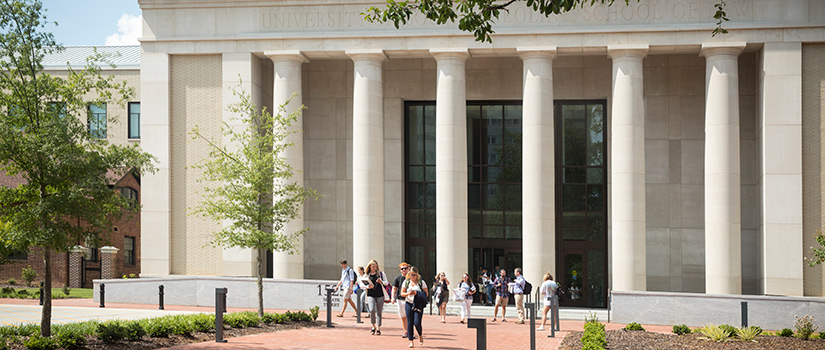 students walking on brick pathway in front of the School of Law.