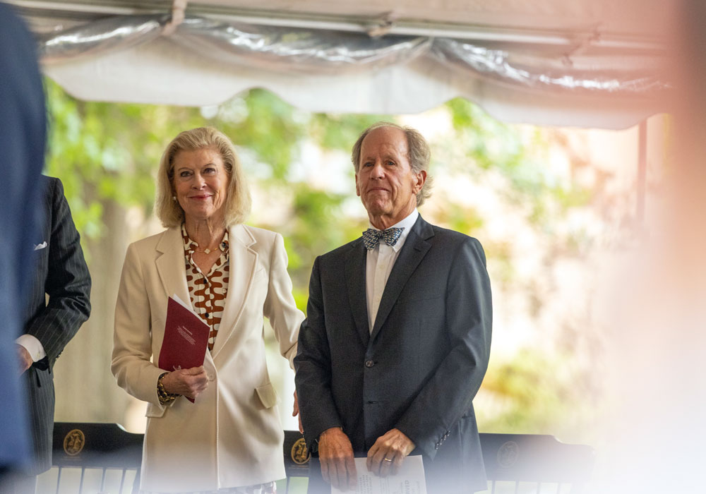 man and woman stand in front of chairs
