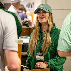 Student wearing Masters gear talking to customers at the Masters.