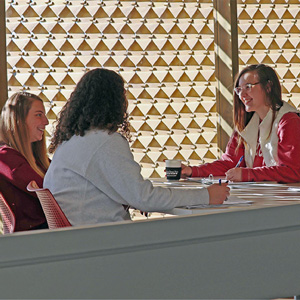 Students sit at a table with a textured wall in the background