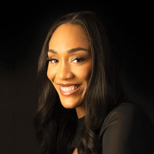 Aja Wilson smiles for the camera on a black background.