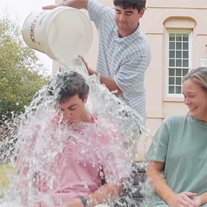 A student pours a bucket of ice water on Wade Jefferson, splashing another student.
