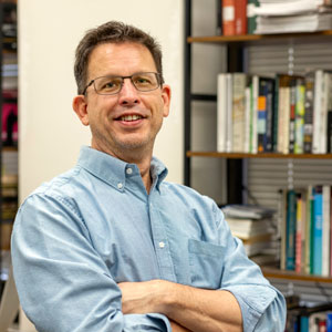 man stands in front of a bookcase
